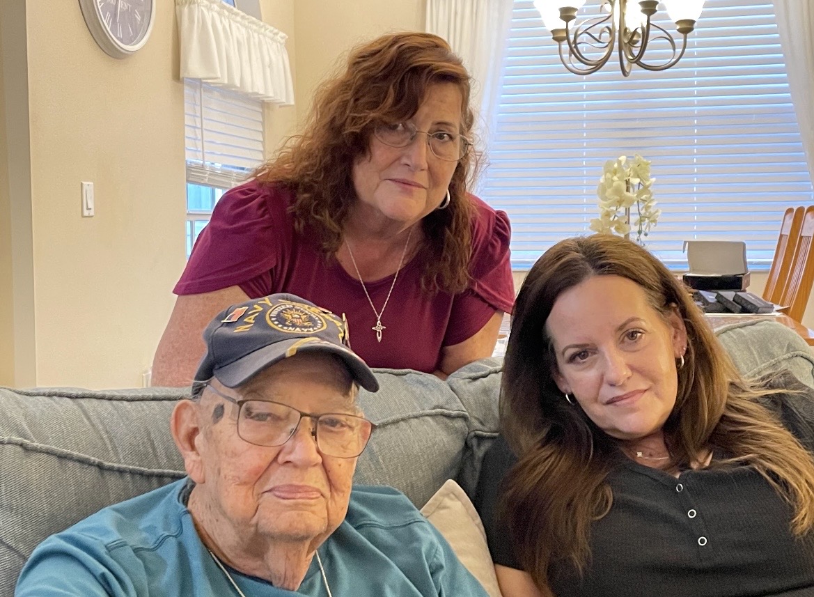 Jay seated at home with his daughters Joy and Alice